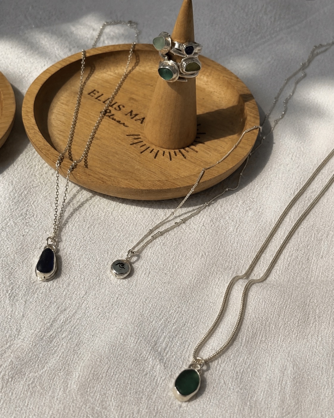 Handmade Ellis Made silver necklaces and sea-glass rings displayed in sunlight